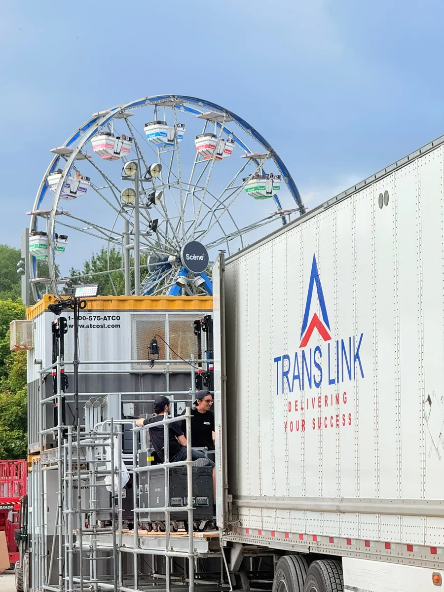Production crew unloading road cases from a Trans Link trailer at a festival