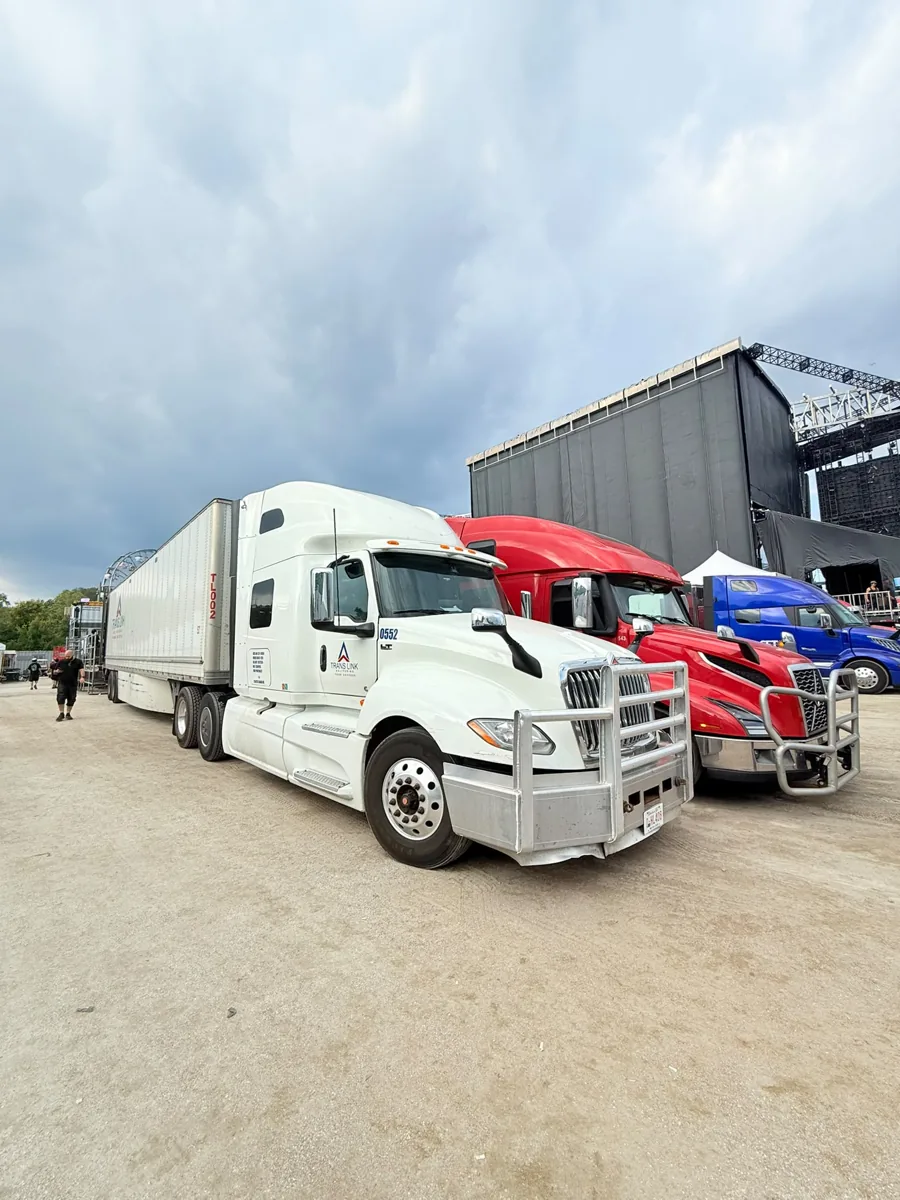 Trans Link truck 0552 and trailer parked beside an outdoor concert stage